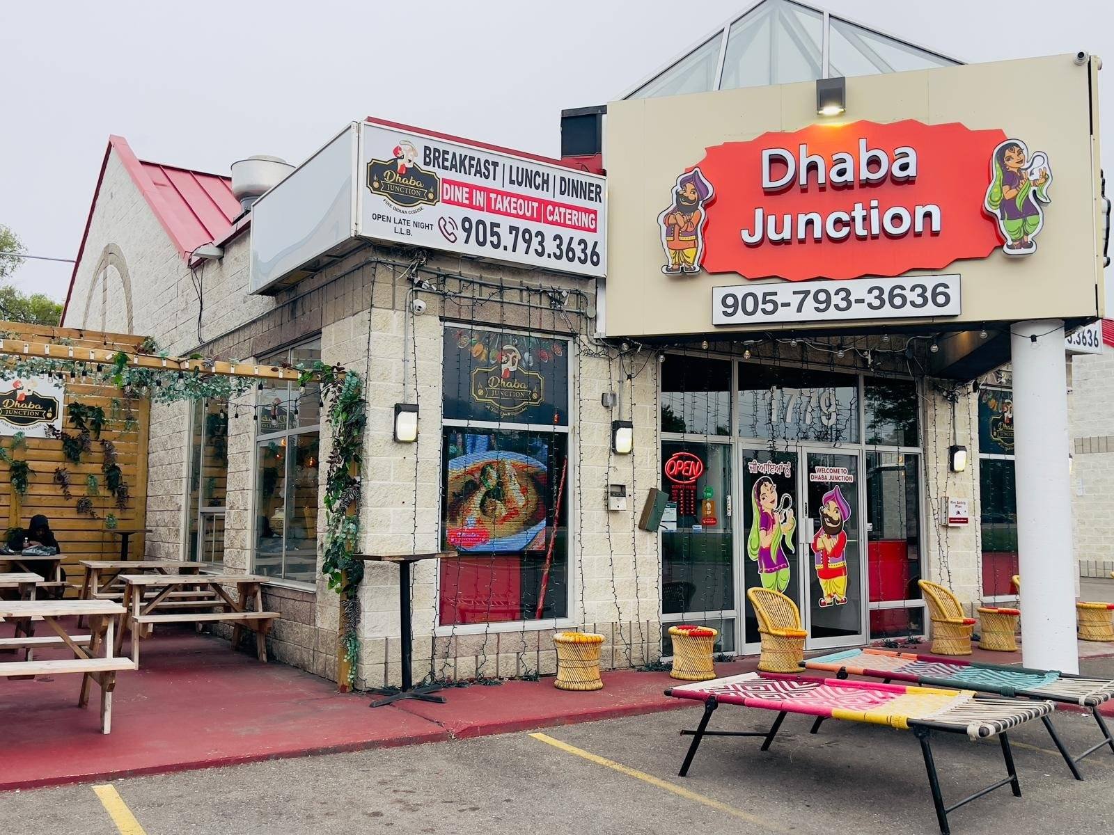 Exterior view of Dhaba Junction restaurant featuring a sign and outdoor seating area.