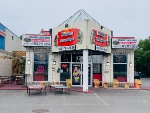 Exterior view of Dhabaj Junction restaurant with signage and seating area.