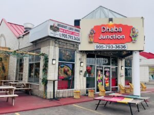 Exterior view of near me Indian restaurant Dhaba Junction featuring signage and outdoor seating area.