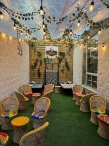 Indoor seating area featuring multiple wicker chairs arranged around a central space with decorative elements. dhaba junction