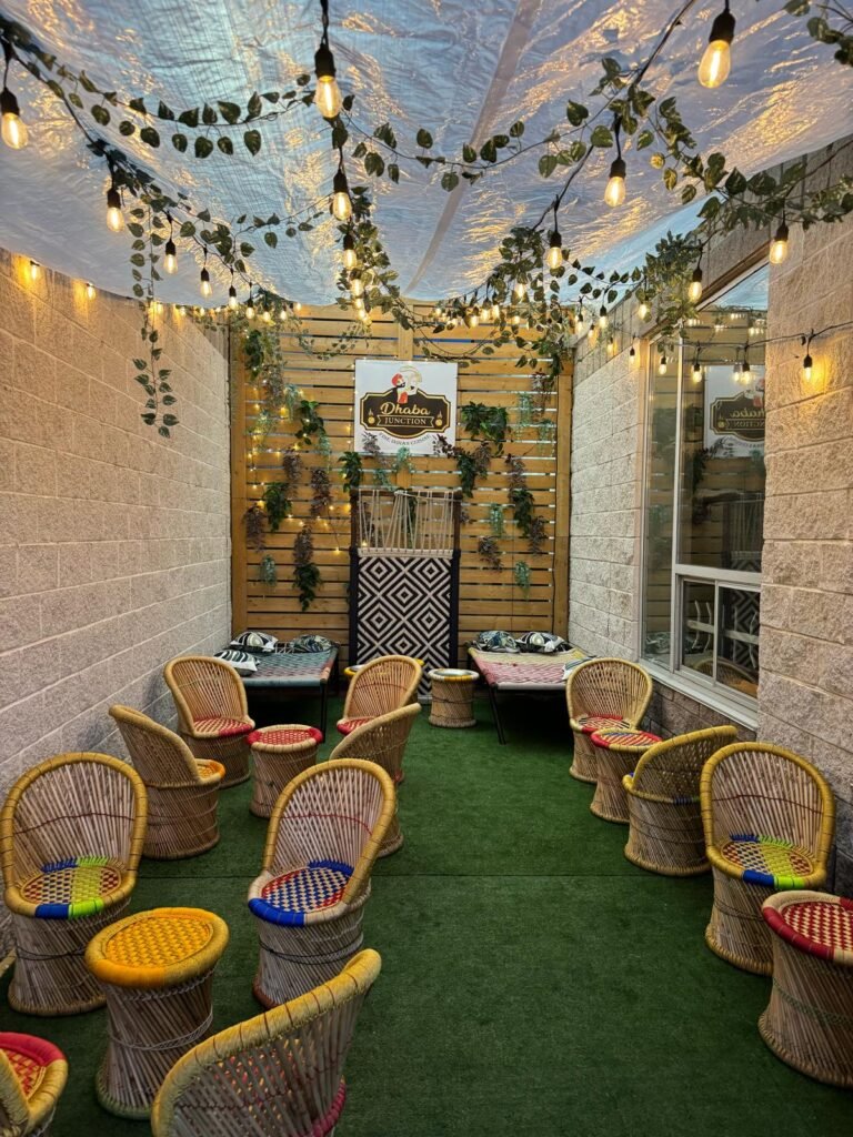 Indoor seating area featuring multiple wicker chairs arranged around a central space with decorative elements. dhaba junction