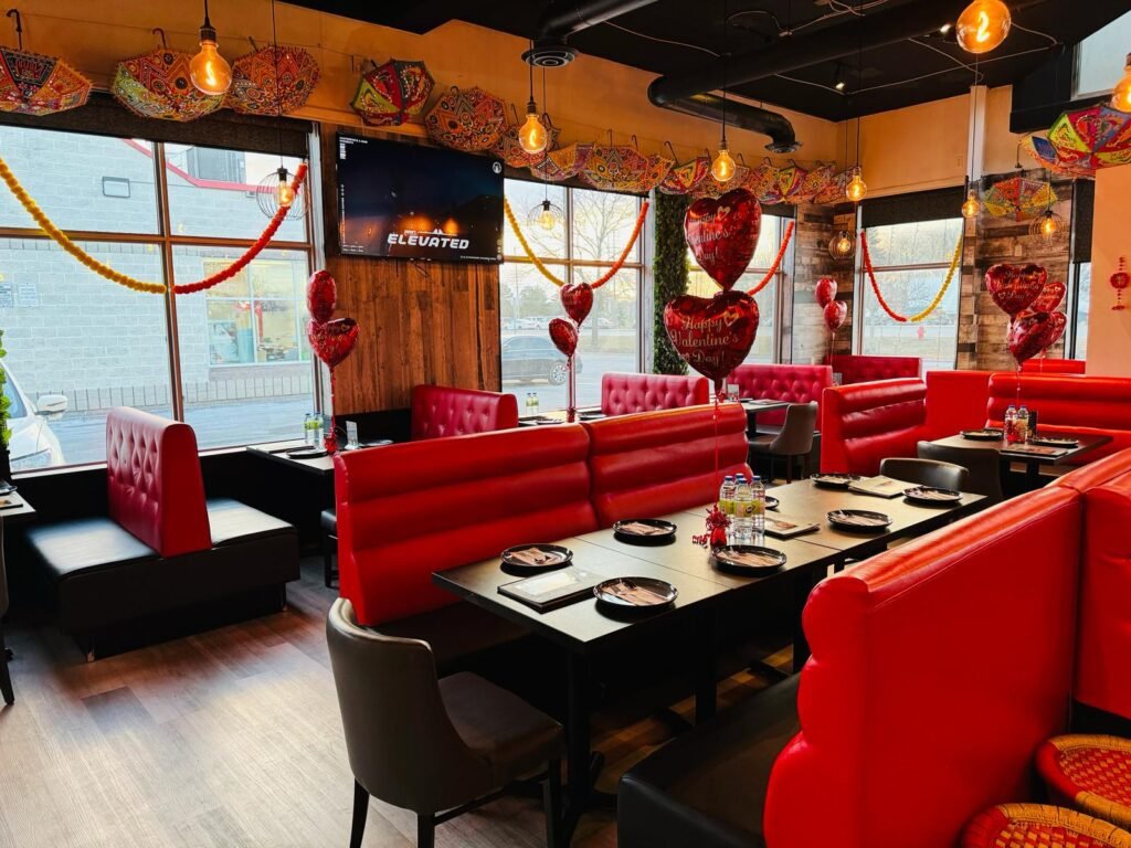 Interior view of a restaurant featuring red booths, tables, and decorative elements for enjoying beautiful weather.