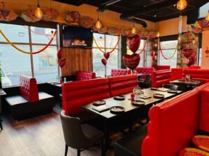 Interior view of a restaurant featuring red booths, tables, and decorative elements for enjoying beautiful weather.